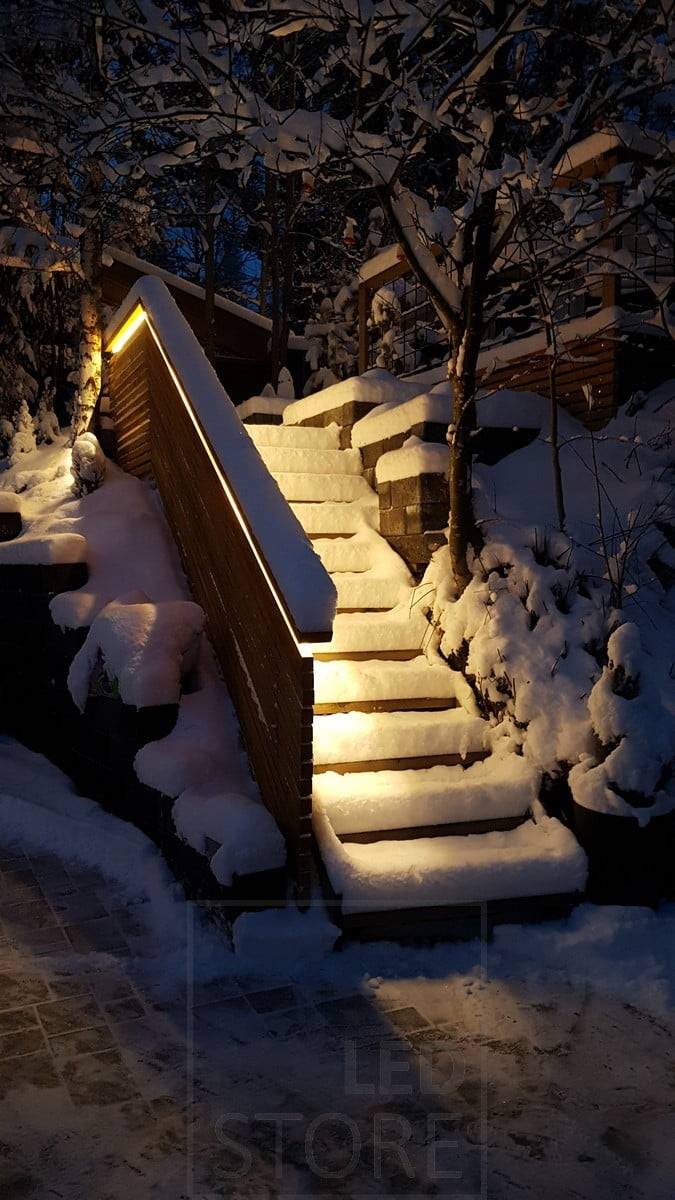 Bande LED sur la rampe d'un escalier extérieur, éclairant indirectement les marches.